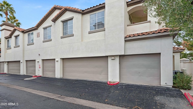 view of front of home with a garage, a tiled roof, and stucco siding