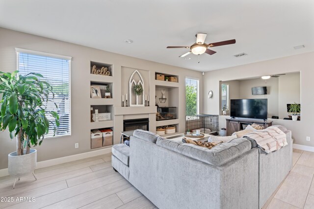 16404 S 18th Dr, Phoenix, AZ 85045 - living area with a ceiling fan, a glass covered fireplace, baseboards, and light wood-type flooring