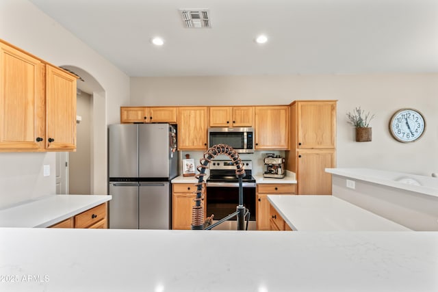 16404 S 18th Dr, Phoenix, AZ 85045 - kitchen featuring appliances with stainless steel finishes, light countertops, arched walkways, light brown cabinetry, and recessed lighting