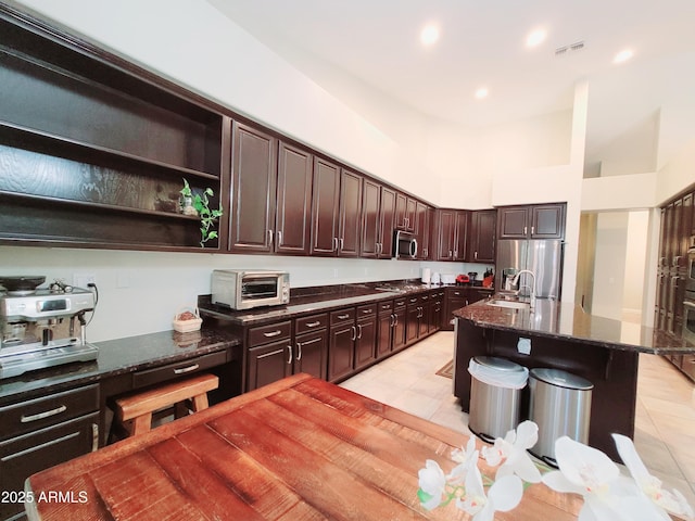 kitchen with dark brown cabinets, stainless steel appliances, light tile patterned floors, a toaster, and visible vents