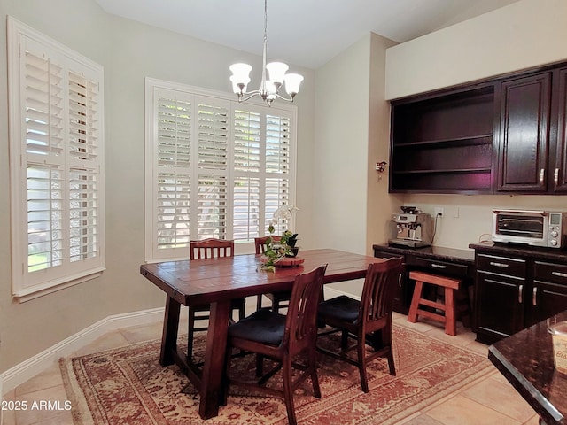 dining area featuring light tile patterned flooring, baseboards, a chandelier, and a toaster