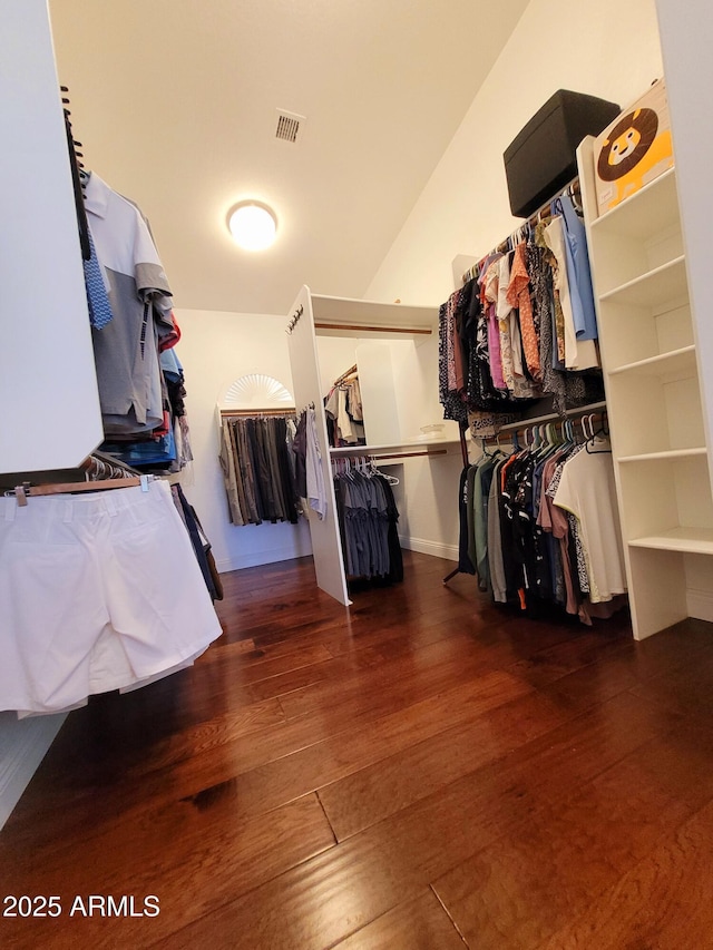 walk in closet with visible vents, wood finished floors, and vaulted ceiling