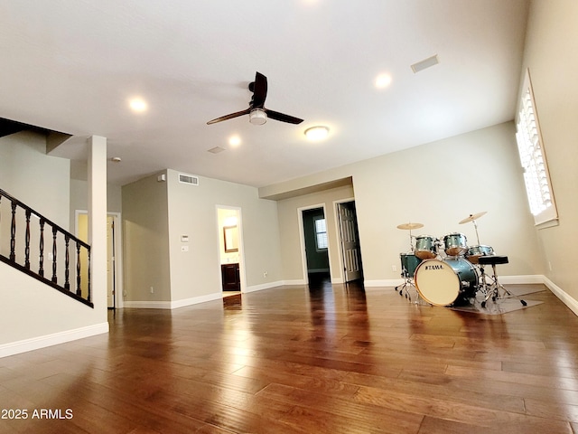 unfurnished living room with a ceiling fan, stairs, hardwood / wood-style floors, and visible vents