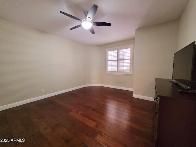 spare room with baseboards, a ceiling fan, and dark wood-type flooring