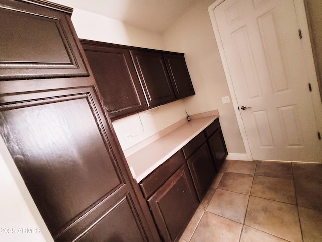 kitchen featuring light countertops, dark brown cabinetry, and light tile patterned flooring