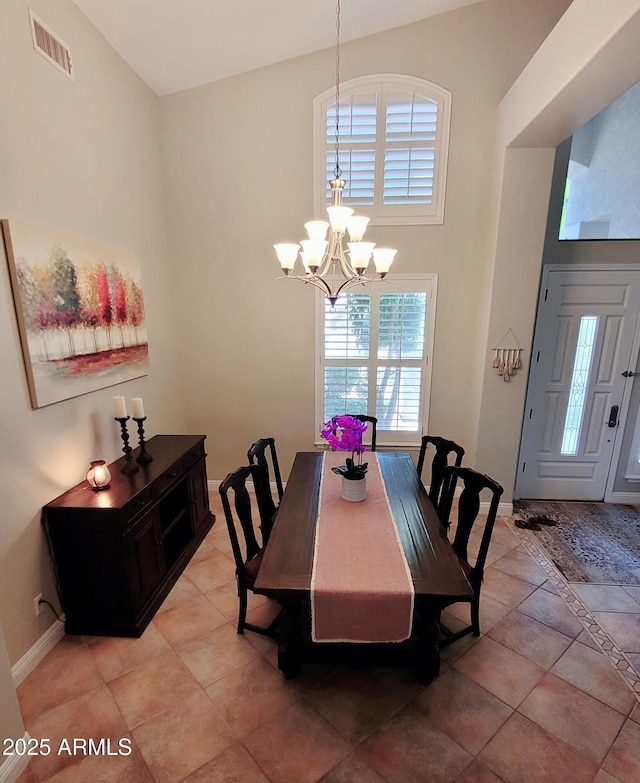 dining space with a chandelier, a high ceiling, visible vents, and baseboards