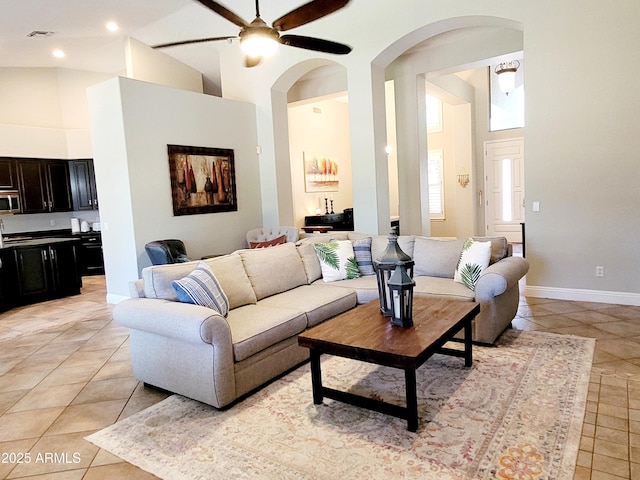 living room with ceiling fan, visible vents, arched walkways, light tile patterned floors, and high vaulted ceiling