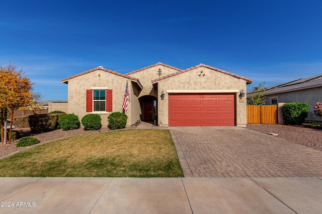 mediterranean / spanish-style home featuring a garage and a front lawn