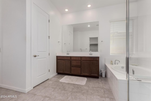 bathroom with tile patterned flooring, vanity, and tiled tub