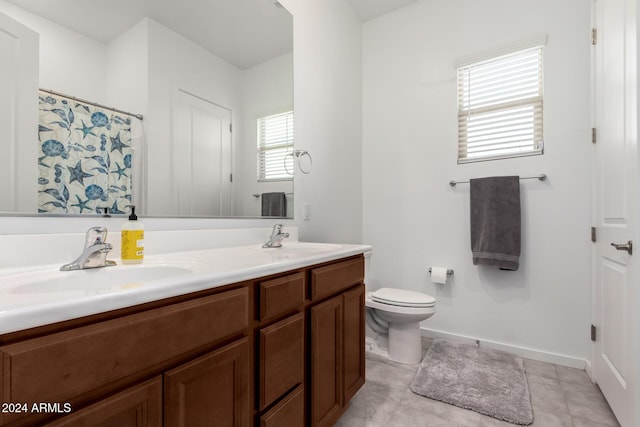 bathroom with tile patterned floors, vanity, a healthy amount of sunlight, and toilet