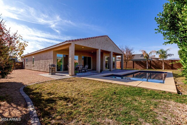 rear view of house featuring a lawn, a patio area, and a swimming pool with hot tub