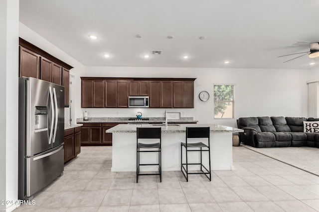 kitchen with a breakfast bar, sink, a kitchen island with sink, and appliances with stainless steel finishes