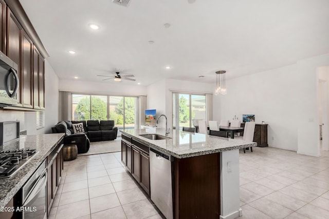 kitchen with stainless steel appliances, ceiling fan, sink, pendant lighting, and a center island with sink