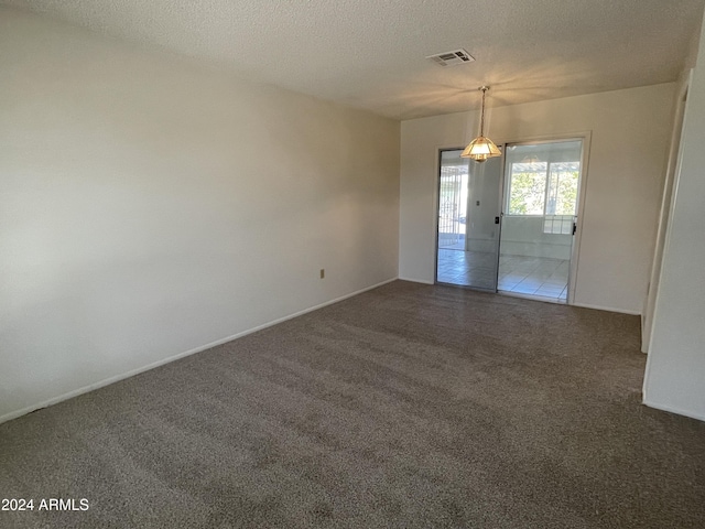 unfurnished room with a textured ceiling and dark carpet