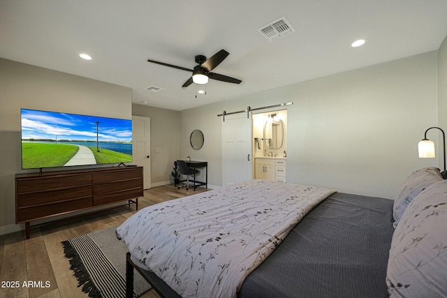 8132 E Valley View Rd, Scottsdale, AZ 85250 - bedroom featuring a barn door, wood finished floors, visible vents, and recessed lighting