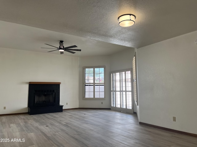 2169 E Bishop Dr, Tempe, AZ 85282 - unfurnished living room featuring wood finished floors, ceiling fan, baseboards, a fireplace with raised hearth, and a textured ceiling