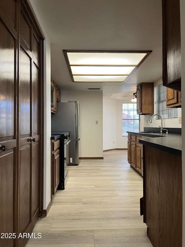 2169 E Bishop Dr, Tempe, AZ 85282 - kitchen featuring black electric range oven, a sink, dark countertops, light wood-type flooring, and baseboards