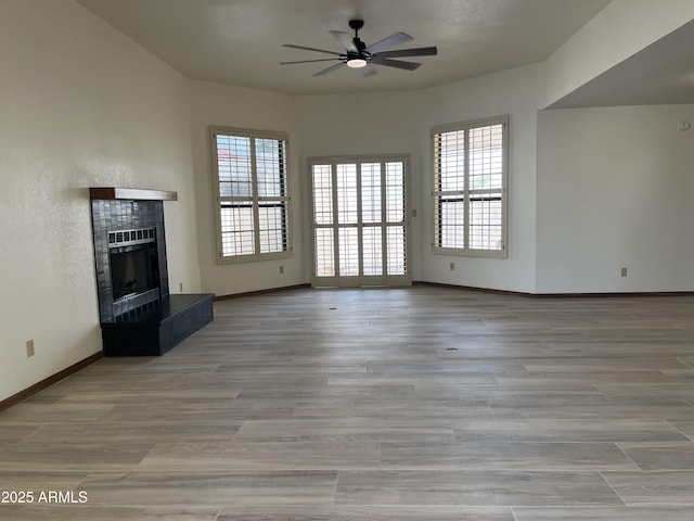 2169 E Bishop Dr, Tempe, AZ 85282 - unfurnished living room featuring a ceiling fan, healthy amount of natural light, a fireplace, and baseboards