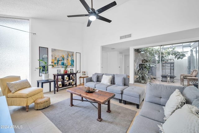 tiled living room featuring ceiling fan, high vaulted ceiling, and a textured ceiling