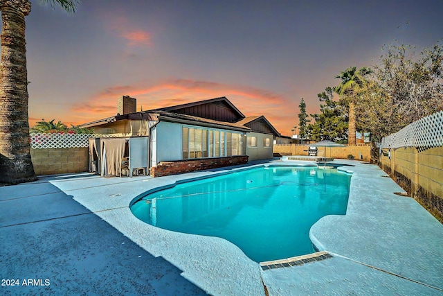 pool at dusk featuring a patio