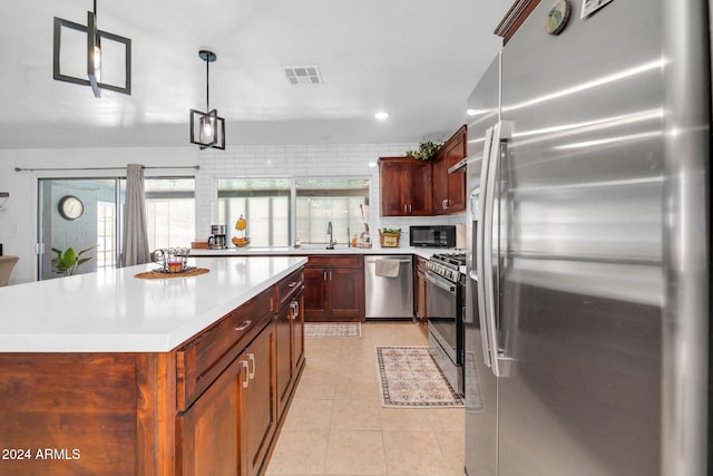 kitchen with hanging light fixtures, light tile patterned floors, a kitchen island, sink, and stainless steel appliances