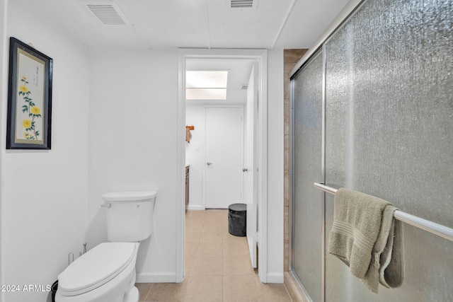 bathroom featuring a shower with door, toilet, and tile patterned flooring