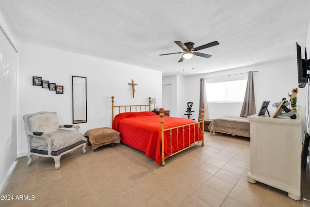 bedroom with a textured ceiling, light tile patterned floors, and ceiling fan