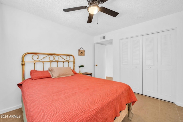 bedroom featuring a closet, a textured ceiling, light tile patterned flooring, and ceiling fan