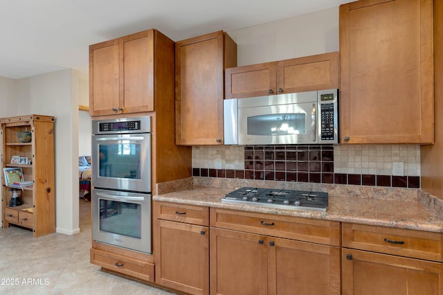 kitchen featuring stainless steel appliances, backsplash, and light stone counters