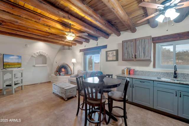 dining space with wood ceiling, ceiling fan, sink, and beamed ceiling