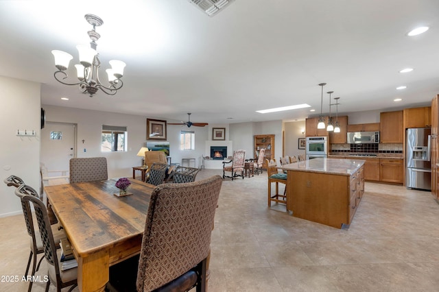 dining area with ceiling fan with notable chandelier