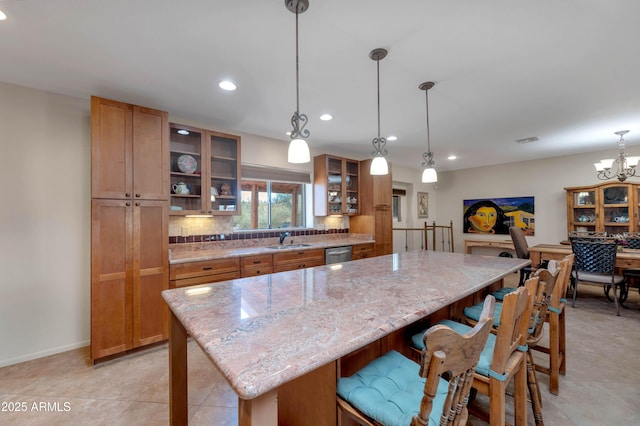 kitchen with sink, a center island, light stone counters, tasteful backsplash, and stainless steel dishwasher