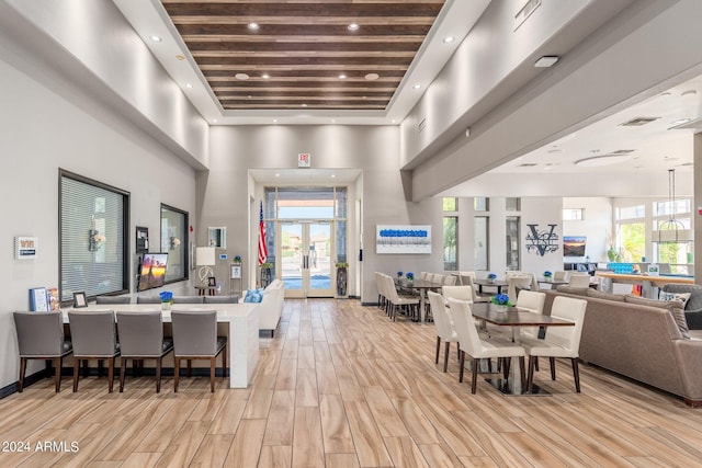 dining room featuring recessed lighting, plenty of natural light, a towering ceiling, and light wood finished floors