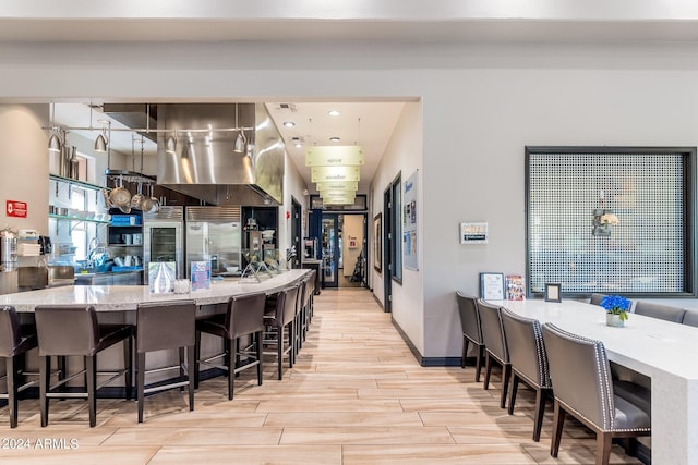 kitchen with a kitchen breakfast bar, light stone counters, and wood tiled floor