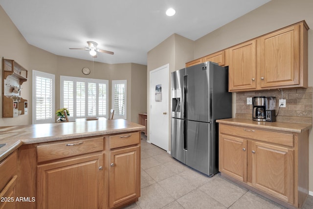 kitchen featuring decorative backsplash, stainless steel fridge, ceiling fan, light tile patterned floors, and kitchen peninsula