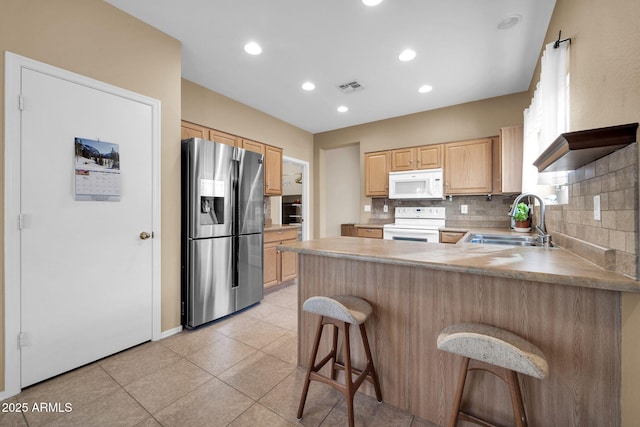 kitchen with sink, range with electric stovetop, kitchen peninsula, stainless steel fridge, and a kitchen bar