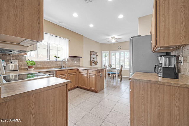 kitchen featuring ceiling fan, sink, stainless steel appliances, kitchen peninsula, and decorative backsplash