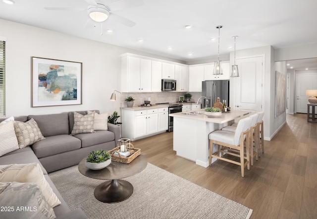 22319 W Monona Ln, Surprise, AZ 85387 - kitchen with appliances with stainless steel finishes, open floor plan, a sink, light wood finished floors, and recessed lighting