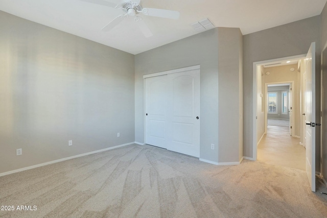 unfurnished bedroom with light carpet, ceiling fan, and a closet