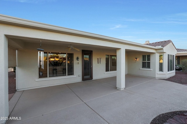 rear view of house with ceiling fan and a patio