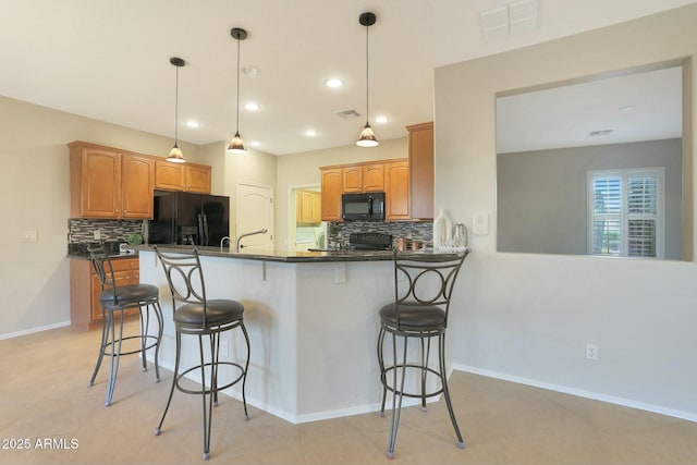 kitchen with pendant lighting, a kitchen bar, kitchen peninsula, and black appliances