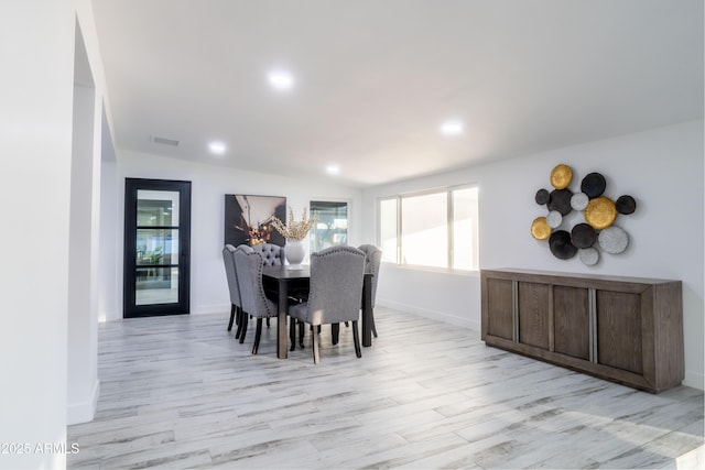 dining space with vaulted ceiling and light hardwood / wood-style flooring