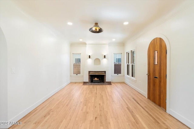 unfurnished living room with ornamental molding, a fireplace, and light hardwood / wood-style flooring