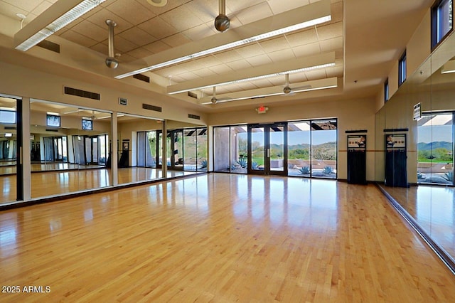 exercise area featuring a high ceiling and light wood-type flooring