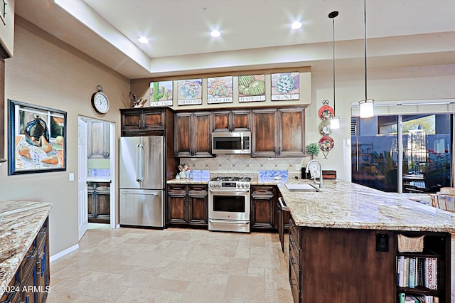 kitchen with sink, appliances with stainless steel finishes, dark brown cabinetry, light stone countertops, and decorative light fixtures