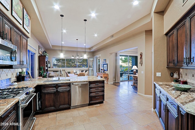 kitchen featuring dark brown cabinets, appliances with stainless steel finishes, a tray ceiling, and hanging light fixtures