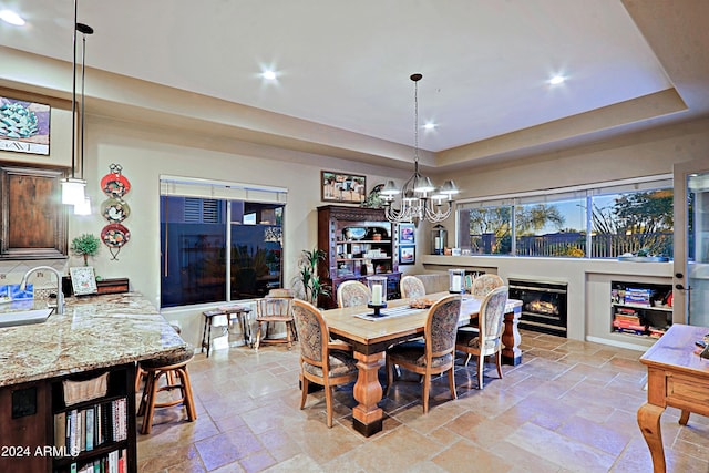 dining area featuring an inviting chandelier, a tray ceiling, and sink