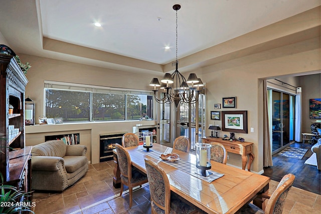 dining area with an inviting chandelier and a tray ceiling