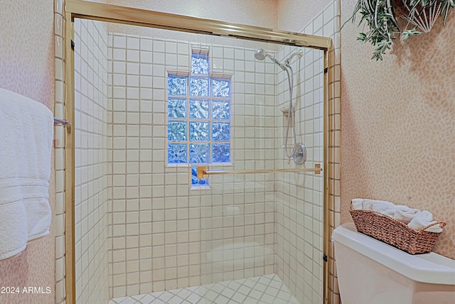 bathroom featuring a shower with door and toilet