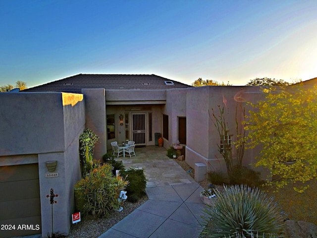 property exterior at dusk with a garage and a patio